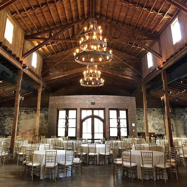 Reception set with gold Chiavari chairs against exposed brick